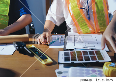 Closeup of team of industrial engineers meeting analyze machinery blueprints consult project on table in manufacturing factory. Working in manufacturing plant or production plant. Closeup of team of industrial engineers meeting analyze machinery blueprints consult project on table in manufacturing factory. Working in manufacturing plant or production plant. 130301629