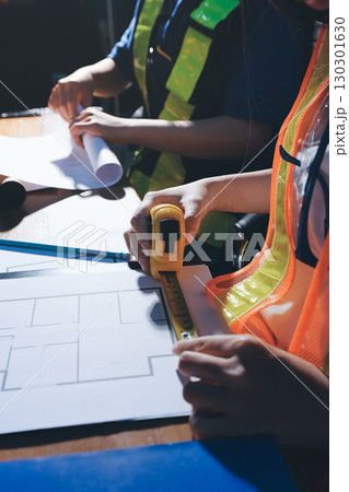 Closeup of team of industrial engineers meeting analyze machinery blueprints consult project on table in manufacturing factory. Working in manufacturing plant or production plant. 130301630