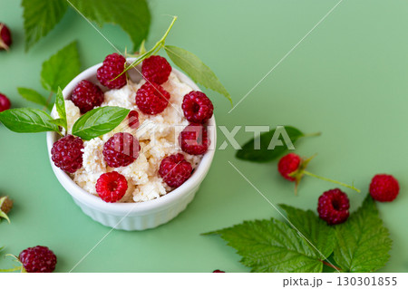 Cottage cheese with raspberries and green leaves on a green background Cottage cheese with raspberries and green leaves on a green background 130301855