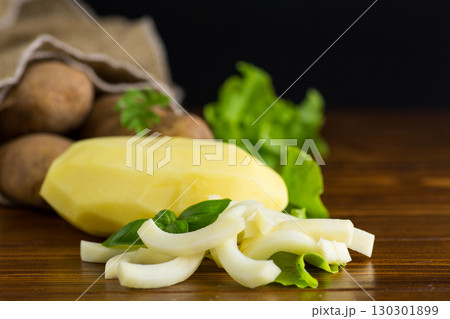 Potatoes in a sack and sliced into strips on a wooden table 130301899