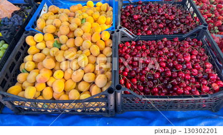 Fresh apricots and cherries displayed in black crates at market. Nutrition, agriculture, and seasonal harvest with natural fruit lifestyle. Fresh apricots and cherries displayed in black crates at market. Nutrition, agriculture, and seasonal harvest with natural fruit lifestyle. 130302201