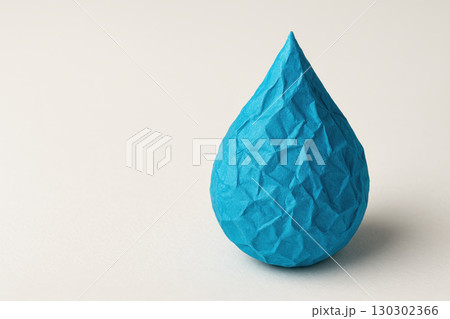 Blue paper art water drop sculpture stands on eco friendly white background, symbolizing sustainability and creativity with textured handmade design for environmental themes 130302366