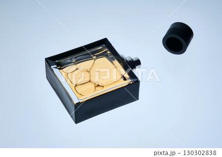 A bottle of perfume with a spray gun on a blue background with an illuminated texture. A bottle of perfume with a spray gun on a blue background with an illuminated texture. 130302838