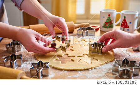 Christmas cookie baking with hands using star-shaped cutters on dough in warm kitchen atmosphere with festive mugs 130303188