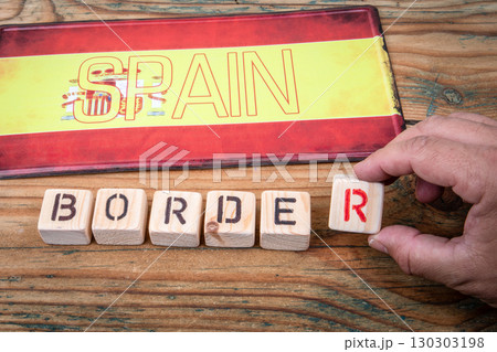Spain border control concept with national flag and wooden letter blocks on rustic table 130303198