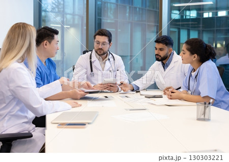A diverse medical team collaborates in a modern office setting. They are engaged in a discussion. A diverse medical team collaborates in a modern office setting. They are engaged in a discussion. 130303221