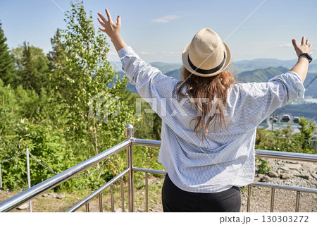 Young caucasian female enjoying scenic mountain view with arms raised Young caucasian female enjoying scenic mountain view with arms raised 130303272