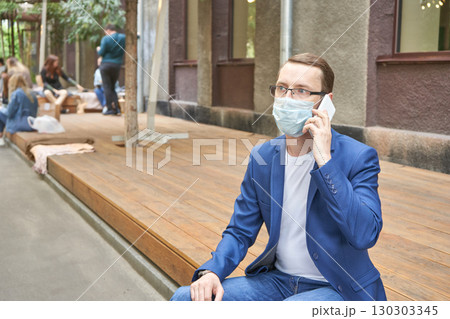 Caucasian male adult sitting on bench wearing face mask and glasses 130303345