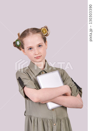 Young caucasian female child holding tablet in olive dress with fruit hair clips Young caucasian female child holding tablet in olive dress with fruit hair clips 130303390