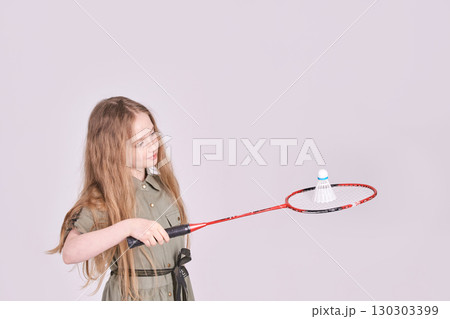 Caucasian young girl playing badminton with racket and shuttlecock against plain 130303399