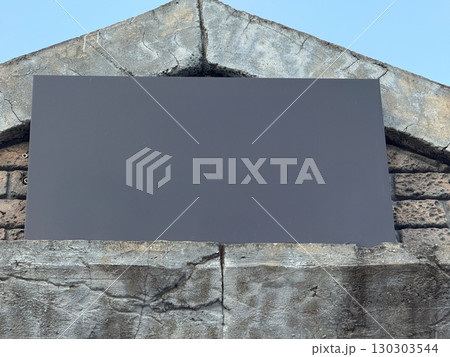 Blank black signboard on stone wall background. Copy space, information board, and urban architecture for message or design placement. Blank black signboard on stone wall background. Copy space, information board, and urban architecture for message or design placement. 130303544