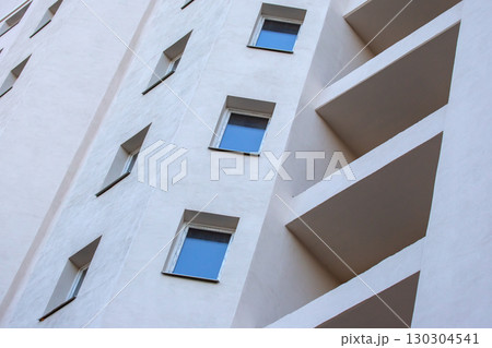 Modern apartment building exterior with geometric design and blue windows Modern apartment building exterior with geometric design and blue windows 130304541