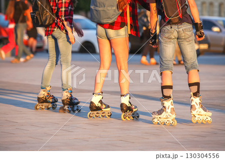 Group of friends skating on rollerblades in bright afternoon light at a city park Group of friends skating on rollerblades in bright afternoon light at a city park 130304556