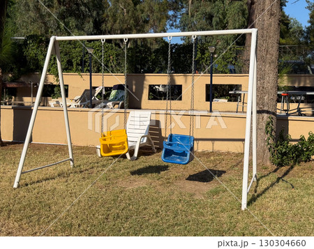 Colorful playground swings outdoors. Childhood, playtime, and leisure in the garden. 130304660