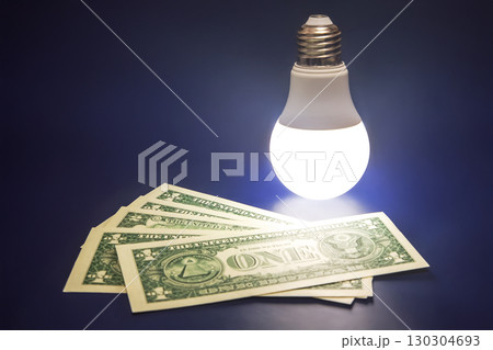 Light bulb illuminating money symbolizes energy savings and cost reduction strategies 130304693