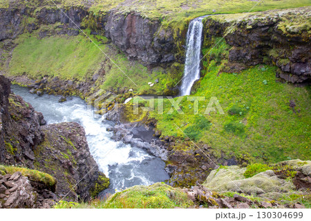 Majestic waterfall cascading into lush green canyon in Iceland's nature 130304699