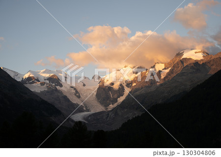 Early morning casts warm light on Piz Bernina, showcasing its towering peaks and glaciers. The serene alpine landscape invites exploration in the heart of Switzerland. Early morning casts warm light on Piz Bernina, showcasing its towering peaks and glaciers. The serene alpine landscape invites exploration in the heart of Switzerland. 130304806