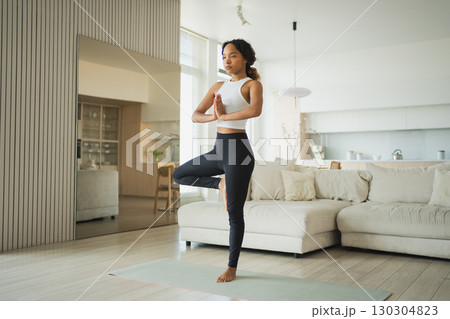 Yoga fitness workout training. Healthy African girl practicing yoga at home. Woman training Pilates doing sports exercise on yoga mat indoor. Girl have training workout for weight loss. Sport fitness 130304823