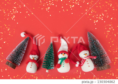 Christmas red background with knitted snowmen in red hats and Christmas trees with golden lights and space for text, greetings, promotions, and discounts. Christmas and New Year card. 130304862
