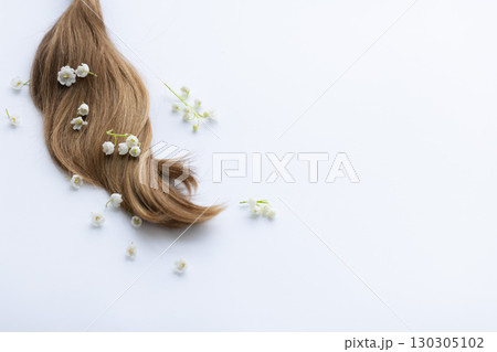 Female hair and lily of the valley flowers. On a white background with a copy space. Female hair and lily of the valley flowers. On a white background with a copy space. 130305102