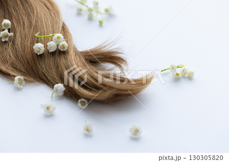 Female hair and lily of the valley flowers. On a white background. Female hair and lily of the valley flowers. On a white background. 130305820
