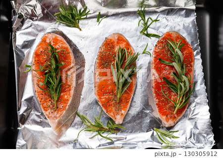 Raw salmon fillets with herbs on foil in baking tray, perfect for healthy cooking Raw salmon fillets with herbs on foil in baking tray, perfect for healthy cooking 130305912
