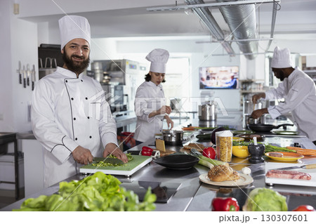 In a professional kitchen, male cook preparing gourmet meals by using cutting boards and chopping ingredients. Chef cooking with fresh produce, doing food prep for tasty dishes, gastronomy. In a professional kitchen, male cook preparing gourmet meals by using cutting boards and chopping ingredients. Chef cooking with fresh produce, doing food prep for tasty dishes, gastronomy. 130307601