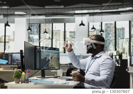 Researcher at work uses virtual reality equipment to plan wind farm and electric grids layouts. RD professional using VR glasses to oversee alternative energy based power lines and VAWT turbines 130307607