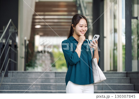 外出先でスマホをチェックする若い女性 外出先でスマホをチェックする若い女性 130307845