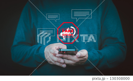 Fake News concept. Person holding a smartphone with a red "FAKE NEWS" warning icon surrounded by chat bubbles, symbolizing misinformation online, manipulate opinion on internet and social media. 130308000