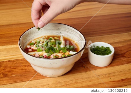 A Freshly Garnished Bowl of Delectable Soup with Chopped Fresh Herbs and Aromatic Seasoning 130308213