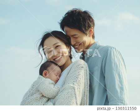 赤ちゃんを優しく抱く若い夫婦の笑顔 130311550