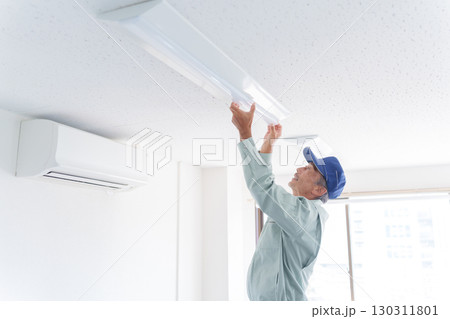 ライトの取付け工事をするシニア男性作業員 130311801