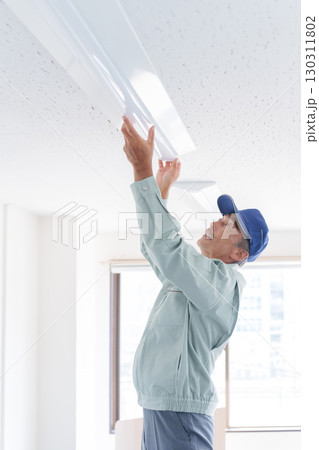 ライトの取付け工事をするシニア男性作業員 130311802