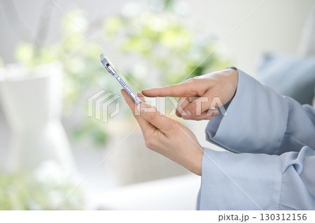 スマホを操作するミドル女性の手元 130312156