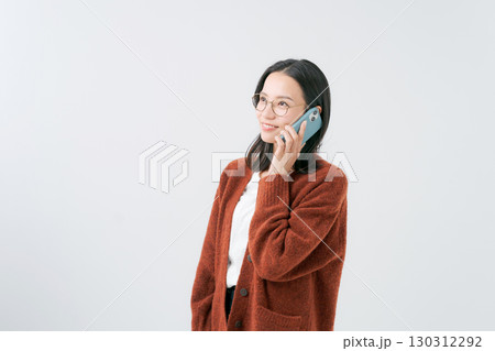 スマホで話すセーターの女性 130312292