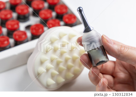 Hand holding trichological serum vial against alopecia 130312834