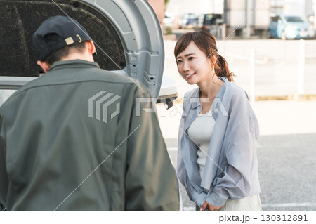ロードサービスに駆けつけた作業員の男性とドライバーの女性 130312891