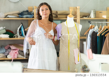 Fashion designer fitting dress on mannequin in dressmaker studio 130313554