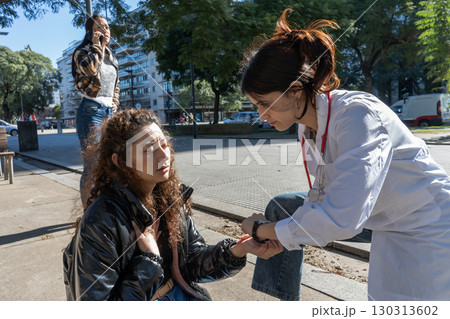 Doctor checking pulse of sick woman on street 130313602