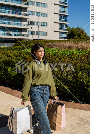 Young woman walking with shopping bags in urban setting 130313612
