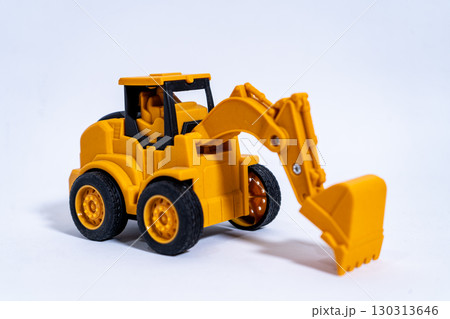 Yellow toy excavator resting on white background Yellow toy excavator resting on white background 130313646