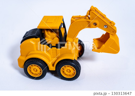 Yellow toy excavator resting on white background Yellow toy excavator resting on white background 130313647