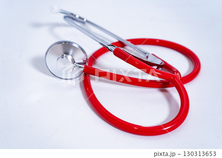 Red stethoscope lying on a white surface representing healthcare 130313653