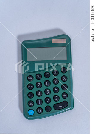 Green pocket calculator lying on white background Green pocket calculator lying on white background 130313670
