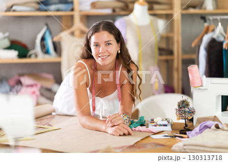 young dressmaker draws a sketch with the help of curved rulers 130313718