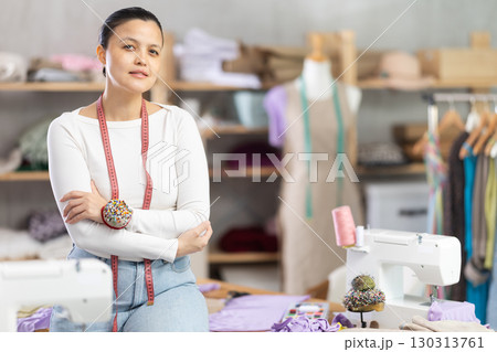 Young female dressmaker posing in sewing workshop 130313761