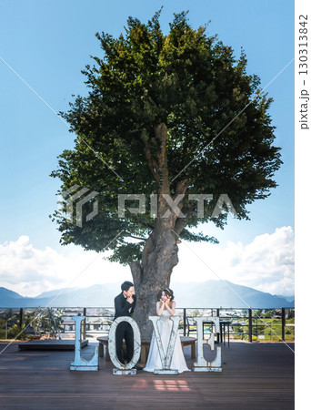 LOVEのオブジェの前でウェディングフォトを撮る新郎新婦 130313842