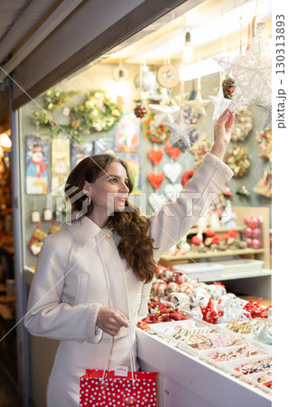 Happy woman choosing gifts and decorations at street Christmas fair 130313893