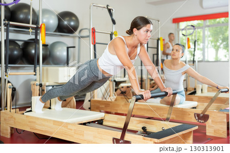 Young girl doing full body exercises lying on reformer device 130313901